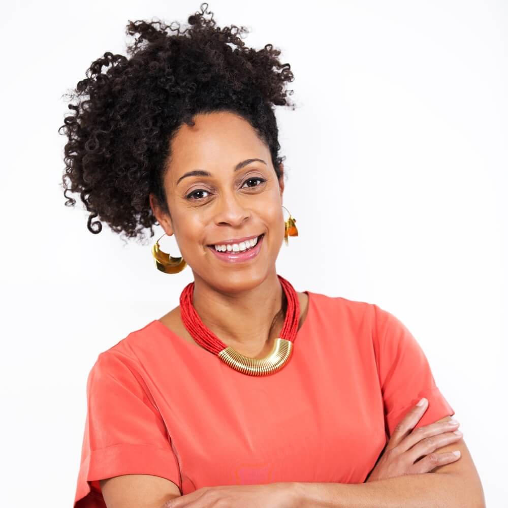 Equality and diversity leader, Remi Harris, wearing a bright coral t-shirt and smiling at the camera